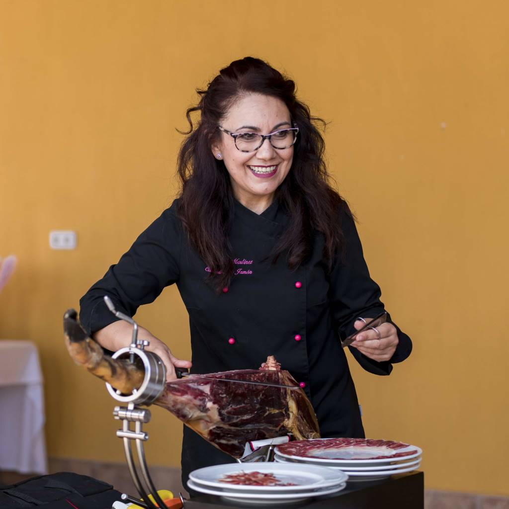Esperanza Martínez cortadora de jamón muy risueña y feliz cortando jamón en un evento. Imagen cercana y amable en un curso cortador de jamón
