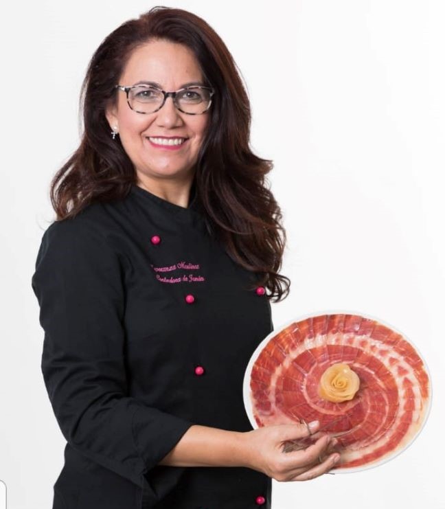 Foto de frente de Esperanza Martínez maestra Cortadora de Jamón Profesional, sosteniendo un plato de jamón en forma de rosa. Imagen portada del curso cortador de jamón